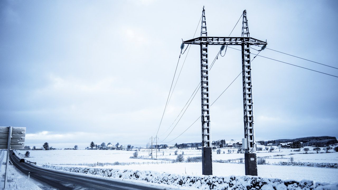 Kraftlinje på Jæren over et snøkledd jorde og langs en bilvei. Foto