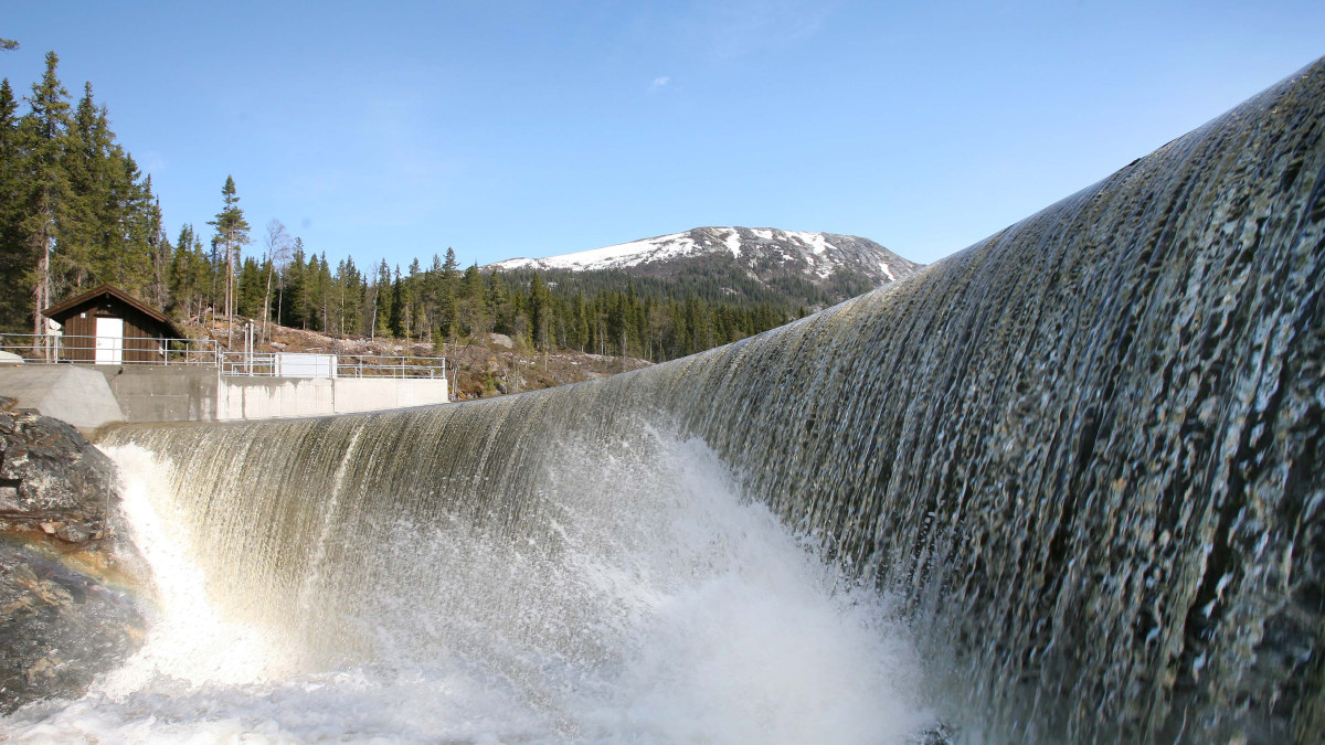 Bilde av vann som fosser ned en dam og et damhus