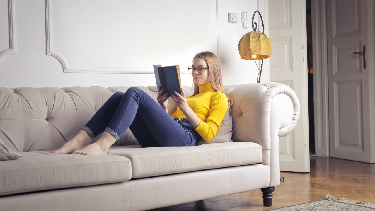 Foto: Dame ligger på sofaen og leser
