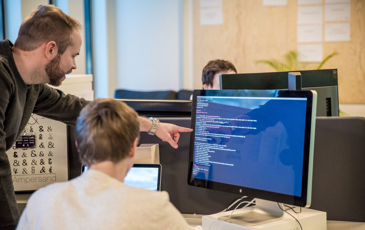 To utviklere foran en skjerm med kode