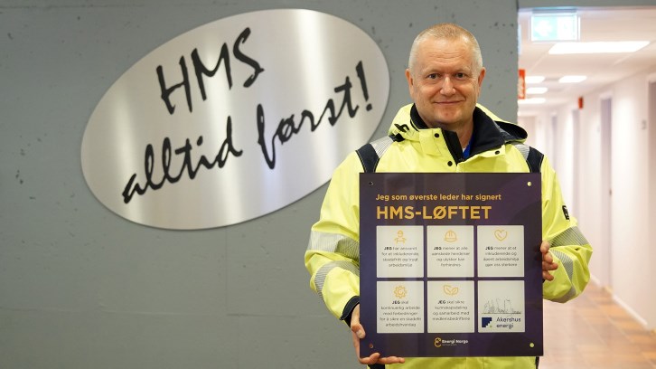 Eskil Lunde Jensen konsernsjef Akershus Energi i arbeidsklær viser fram skiltet med HMS-løftet. Foto