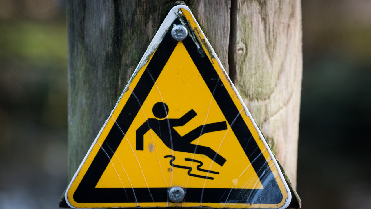 Skilt som viser en person som sklir og faller. Foto