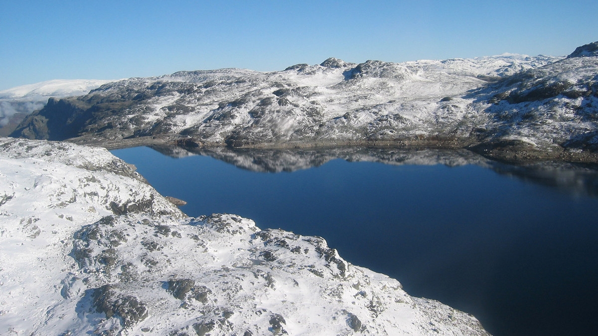 Vann omkranset av snøkledde fjell. Foto