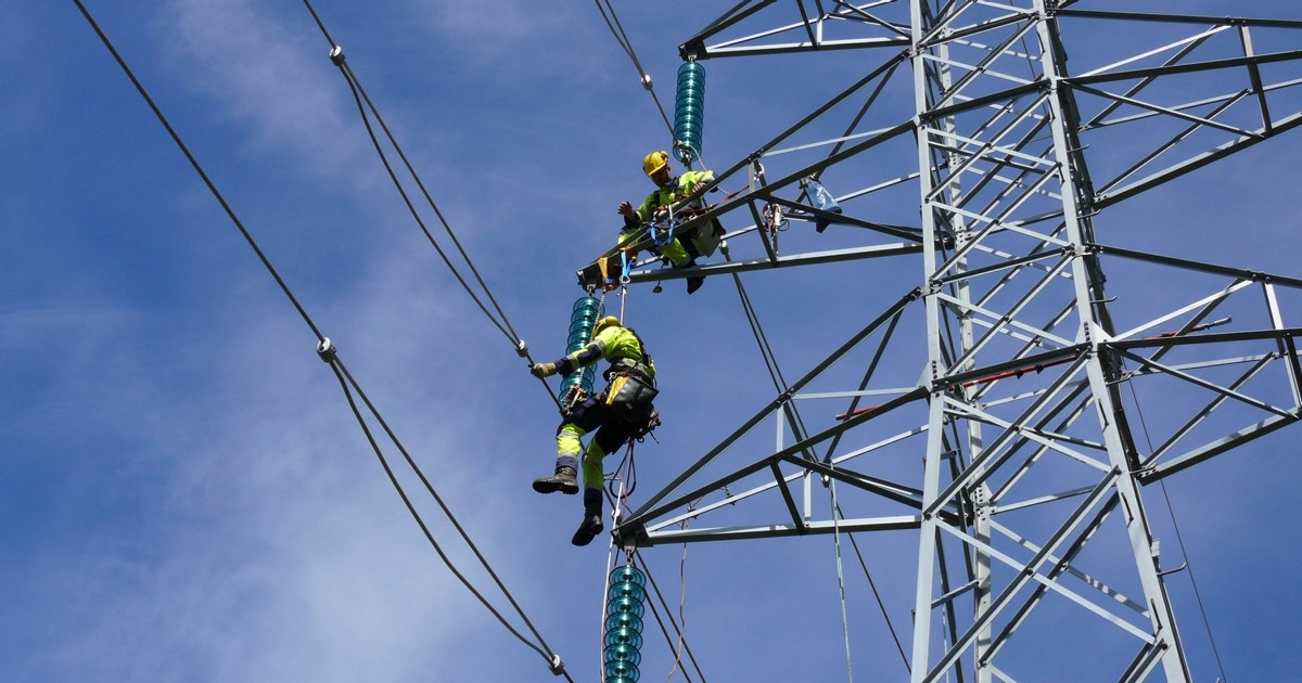 To energimontører klatrer i en kraftmast.