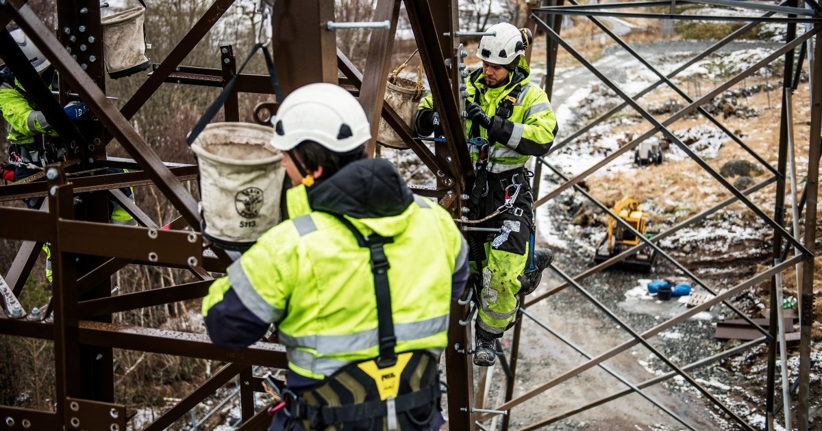 Tre energimontører arbeider i en kraftmast. Foto