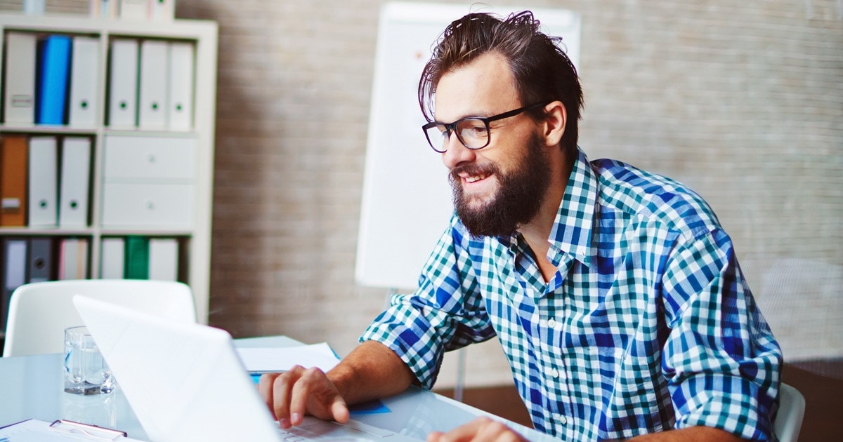 Young businessman in casualwear using laptop in office papirarbeid