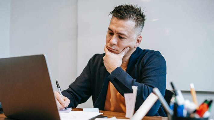 En mann sitter å jobber konsentrert foran en PC.