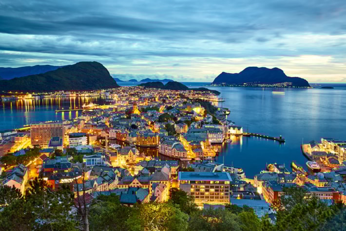 Ålesund havn sette fra en høyde om kvelden med lys i mange vinduer.