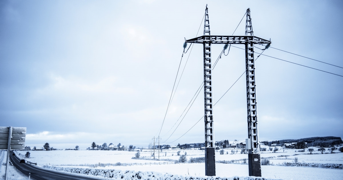 Kraftlinje på Jæren over et snøkledd jorde og langs en bilvei. Foto