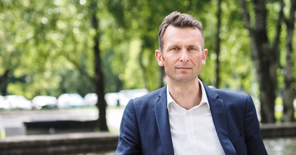 Foto: Knut Kroepelien står foran et basseng med grønne trær i bakgrunnen.