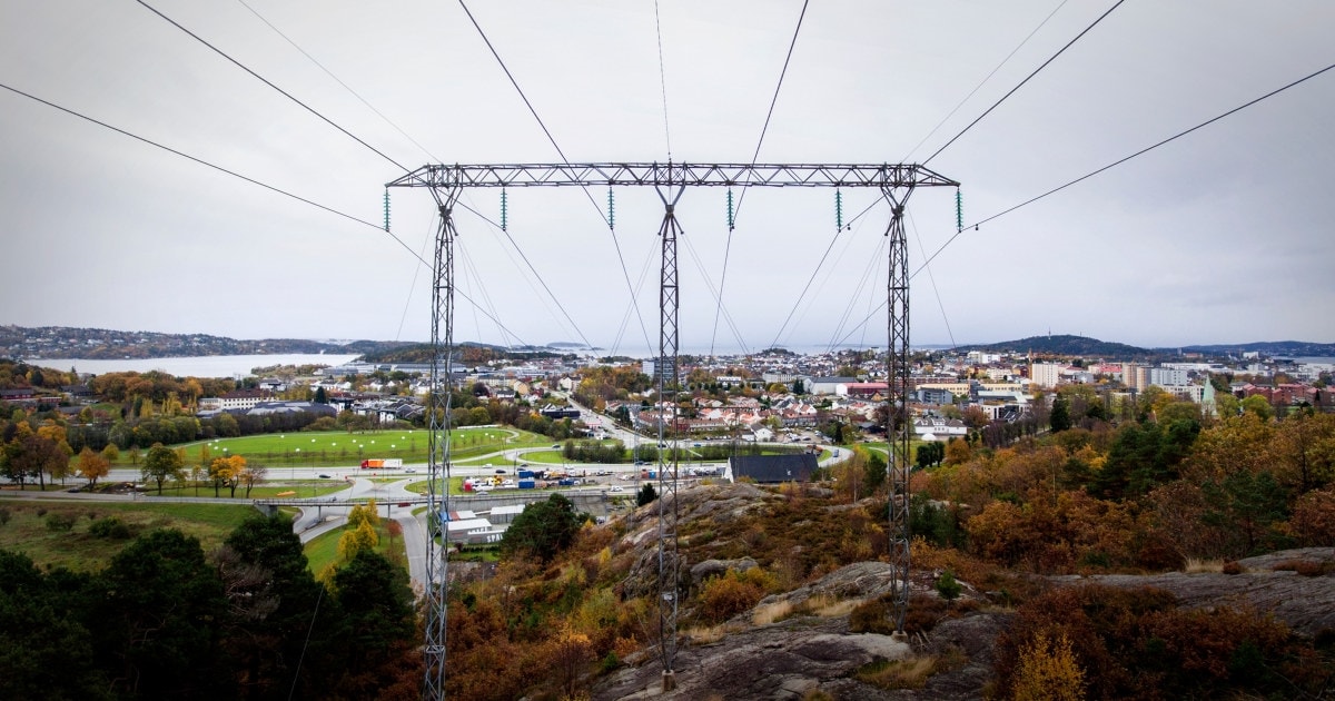 Kraftmast i forgrunnen med by og jorde i bakgrunnen