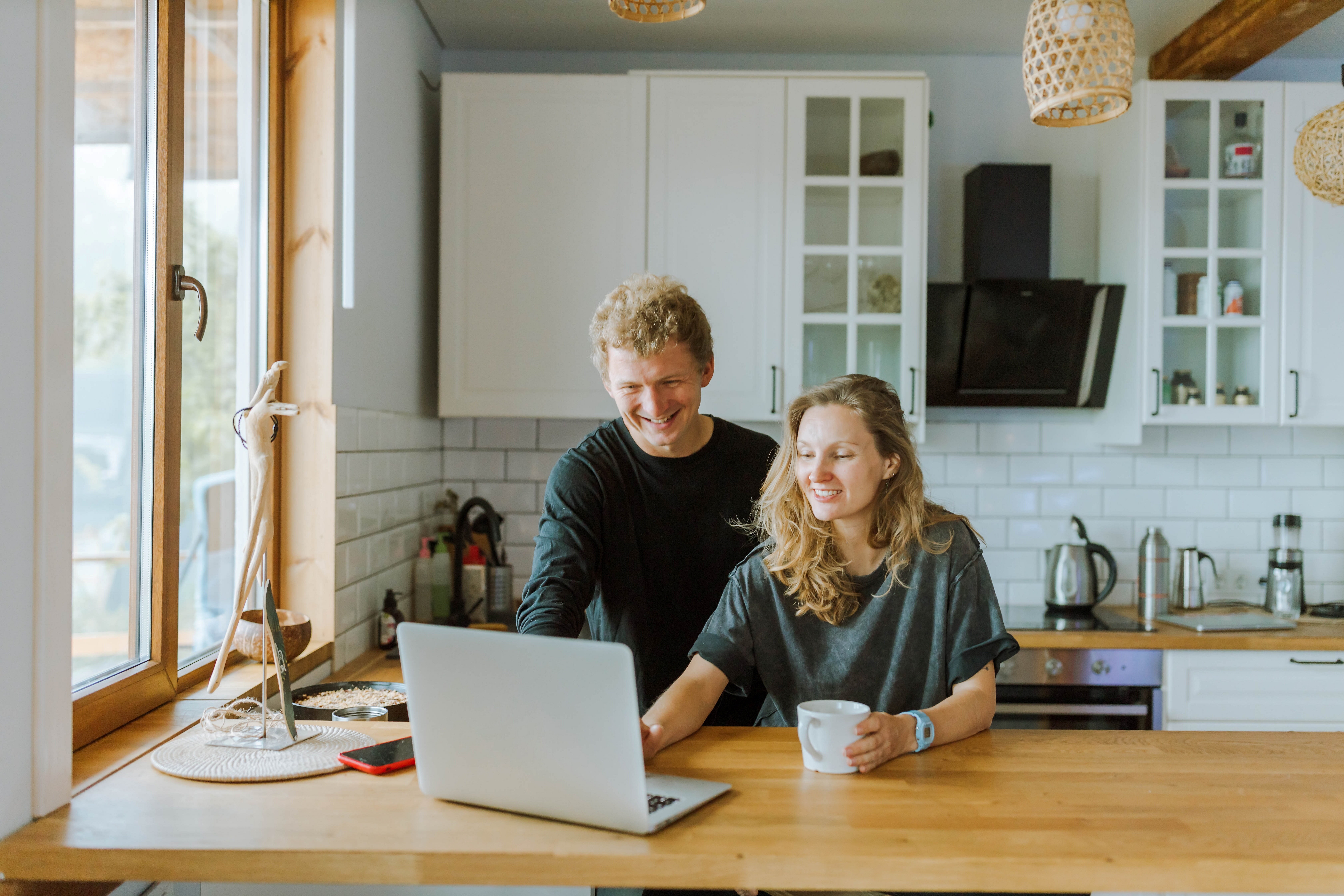 En mann og en dame er på kjøkkenet og ser på en PC. Foto