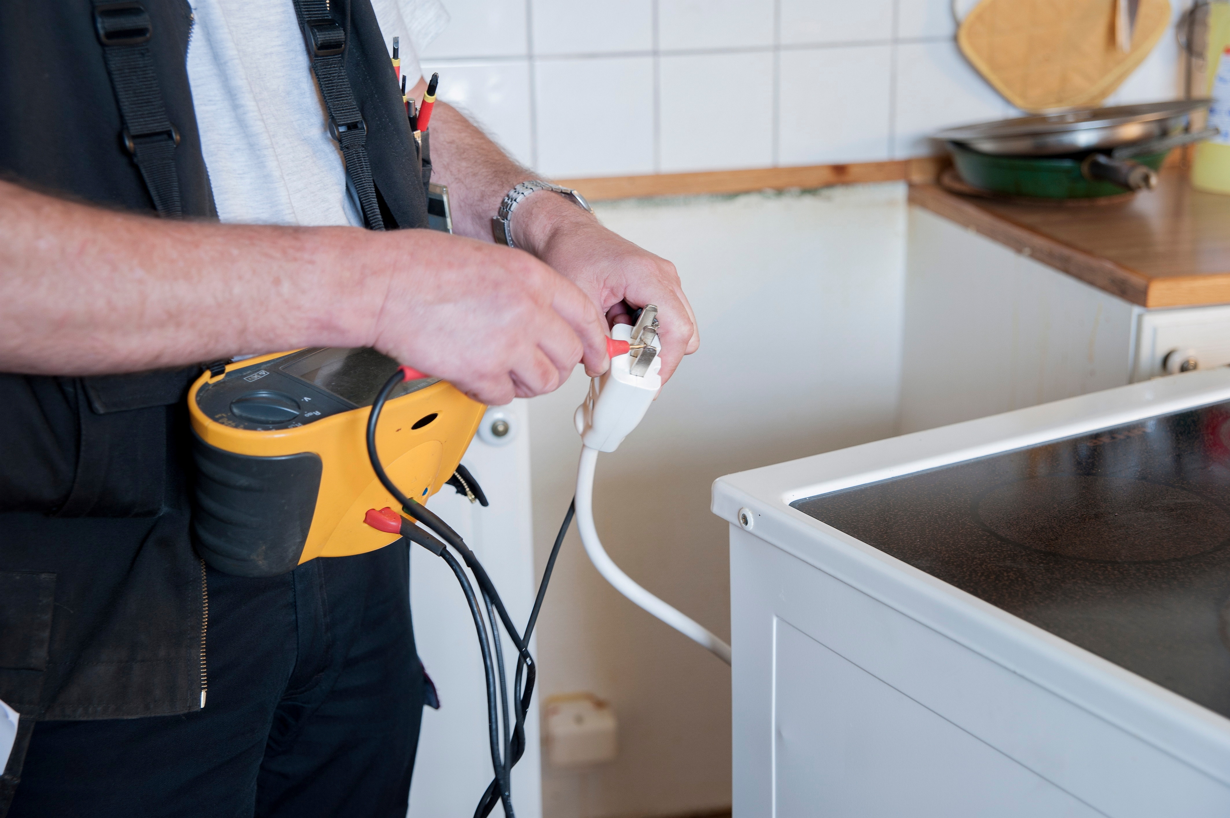 Mann kontrollerer støpslet på en komfyr. Foto