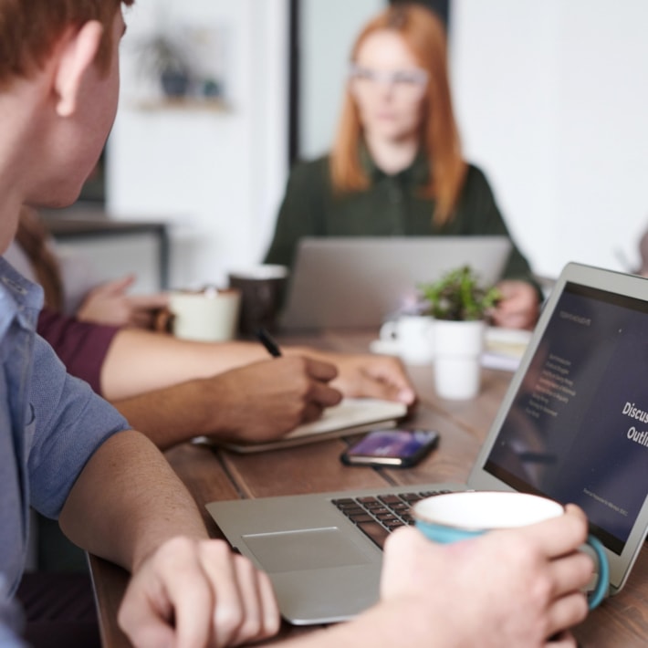 Foto: Mennesker rundt et arbeidsbord med PC.