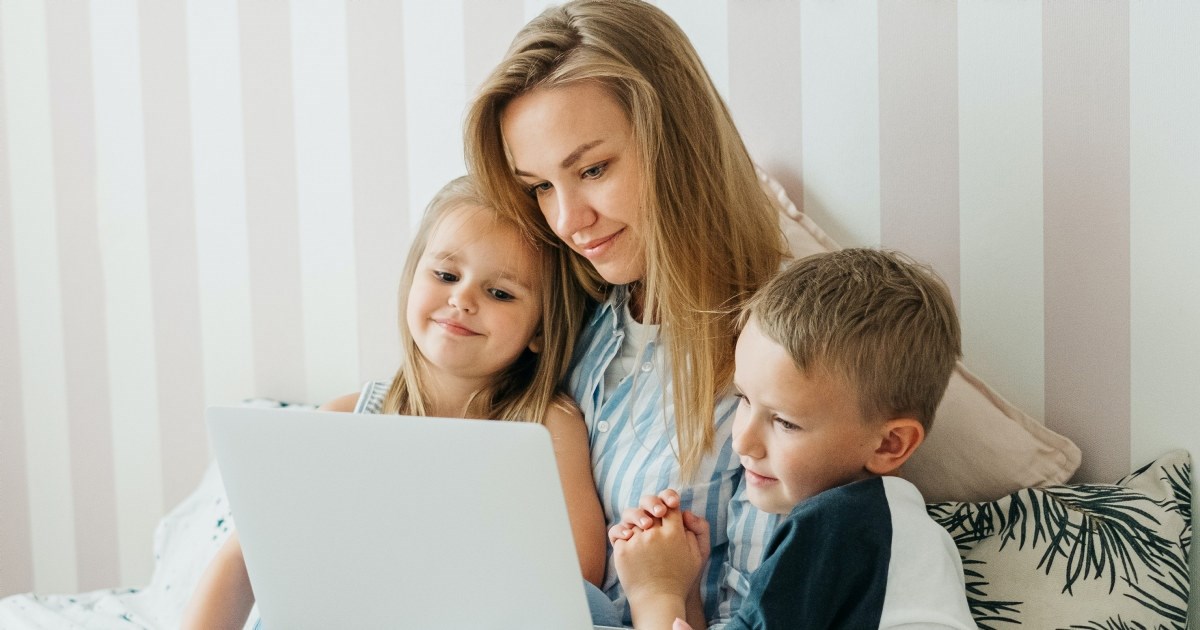 Mor med to barn ser på en PC skjerm. Foto