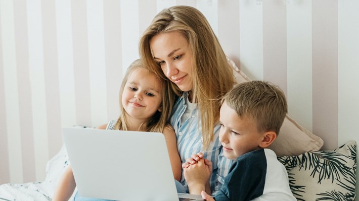 Mor med to barn ser på en PC skjerm. Foto