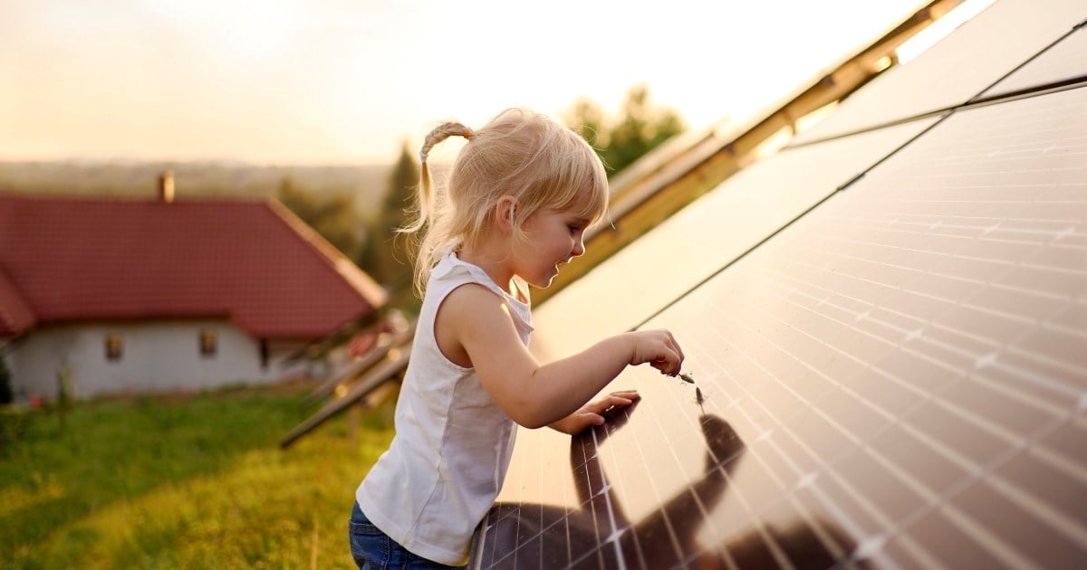 En liten jente tar på et tak med solceller.